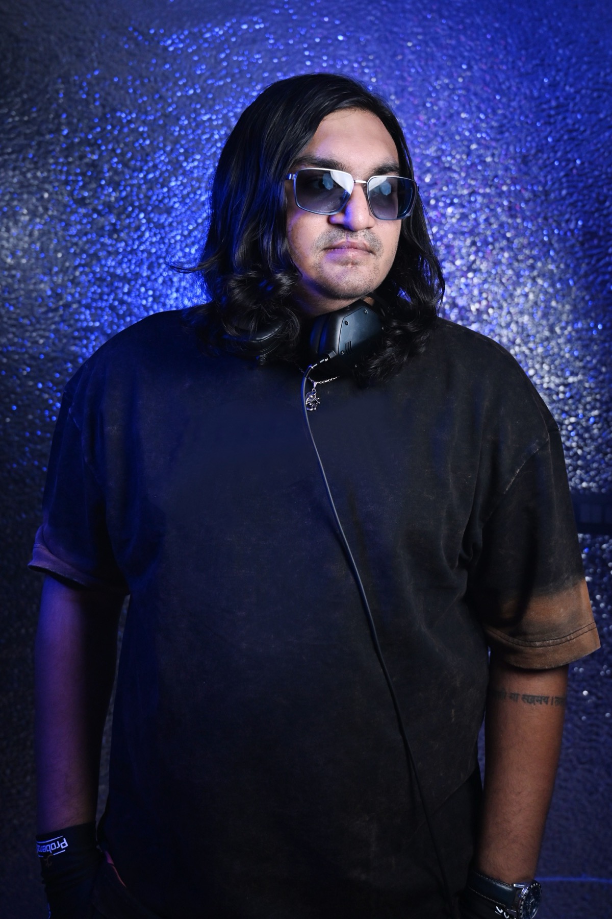 Sidallica standing press portrait with headphones in blue studio light